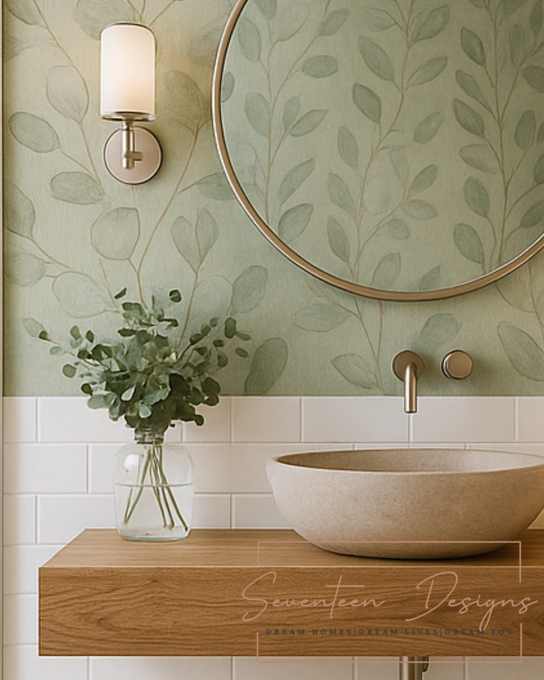 Bathroom interior with green leaf-patterned wallpaper, round mirror, and wooden vanity with Seventeen Designs Logo